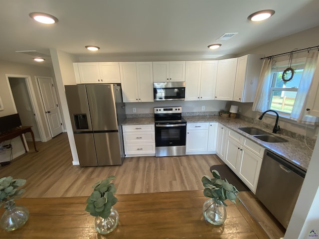 51 Cole Dr, Hawkinsville, GA 31036 - kitchen featuring stainless steel appliances, a sink, white cabinets, light wood finished floors, and light stone counters