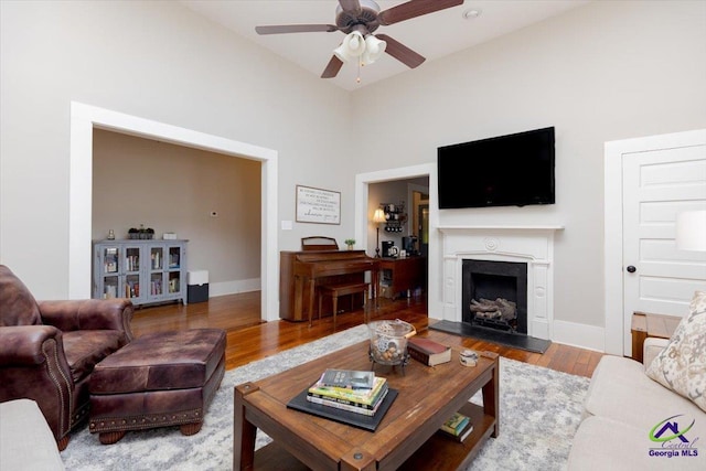 1360 Calhoun St, Macon, GA 31201 - living area featuring ceiling fan, wood finished floors, a fireplace with raised hearth, baseboards, and a towering ceiling