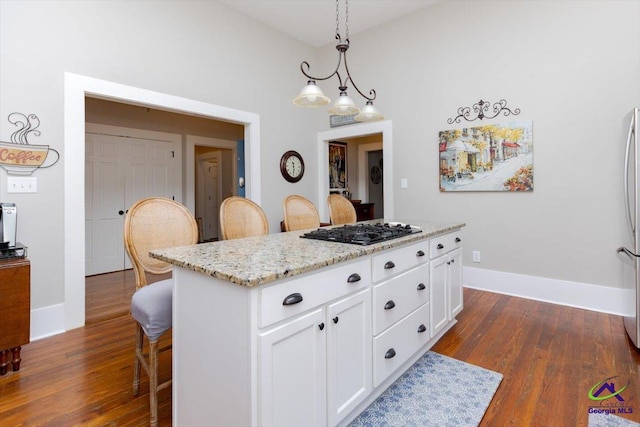 1360 Calhoun St, Macon, GA 31201 - kitchen with black gas stovetop, dark wood-style flooring, a kitchen breakfast bar, and white cabinets