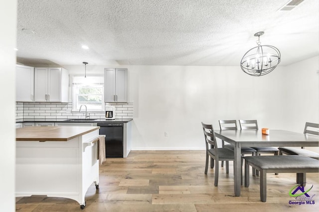 108 Marcia Ct, Warner Robins, GA 31088 - dining area featuring light wood-type flooring, a textured ceiling, a chandelier, and baseboards