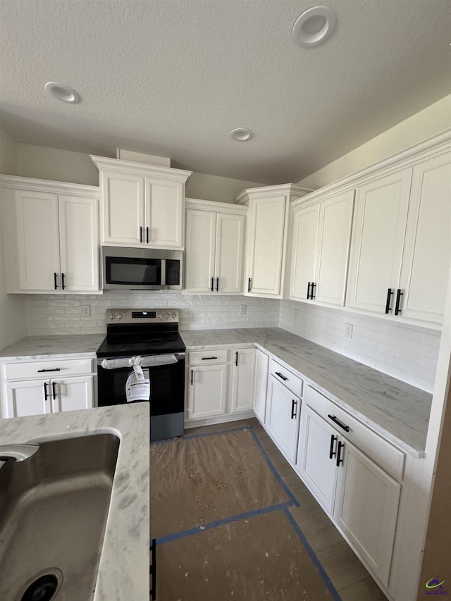 502 Otters Ridge Dr, Kathleen, GA 31047 - kitchen with appliances with stainless steel finishes, white cabinets, tasteful backsplash, and a textured ceiling