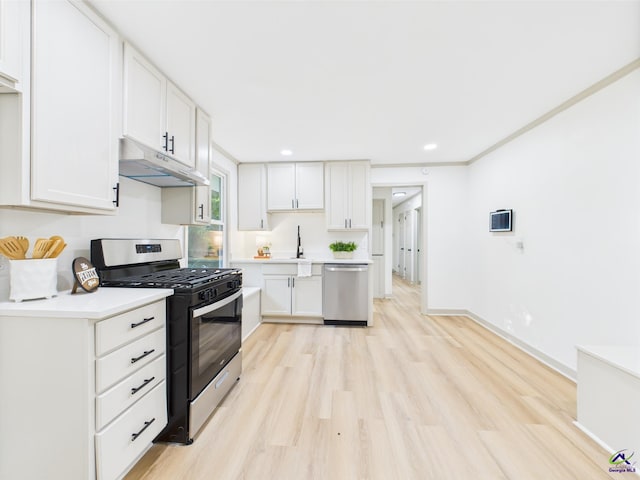 744 Corbin Ave, Macon, GA 31204 - kitchen featuring appliances with stainless steel finishes, under cabinet range hood, light countertops, light wood-style floors, and white cabinets