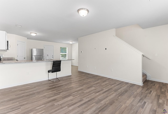 630 Ivy Brook Way, Macon, GA 31210 - kitchen featuring stainless steel appliances, wood finished floors, a peninsula, a kitchen bar, and light stone counters