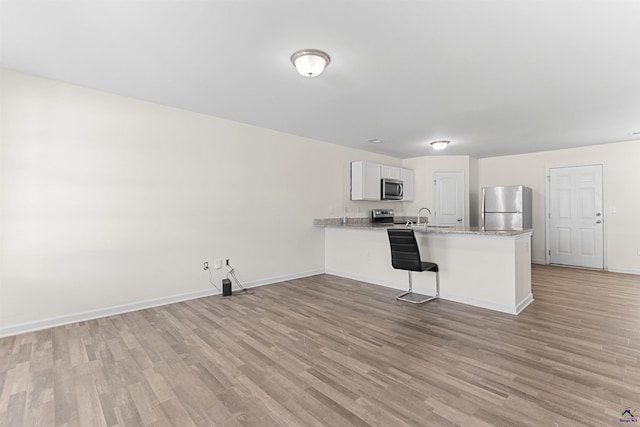 630 Ivy Brook Way, Macon, GA 31210 - kitchen with appliances with stainless steel finishes, a peninsula, light wood-style flooring, and a sink