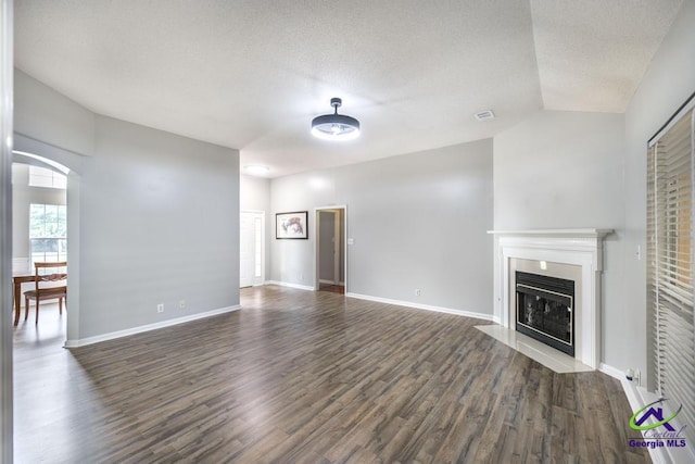 319 Smithville Church Rd, Warner Robins, GA 31088 - unfurnished living room featuring dark wood-style floors, a fireplace with flush hearth, lofted ceiling, baseboards, and a textured ceiling