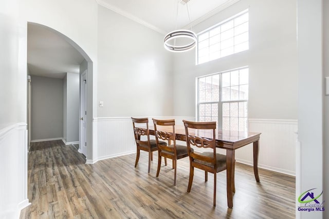 319 Smithville Church Rd, Warner Robins, GA 31088 - dining area with arched walkways, a wainscoted wall, wood finished floors, ornamental molding, and a high ceiling