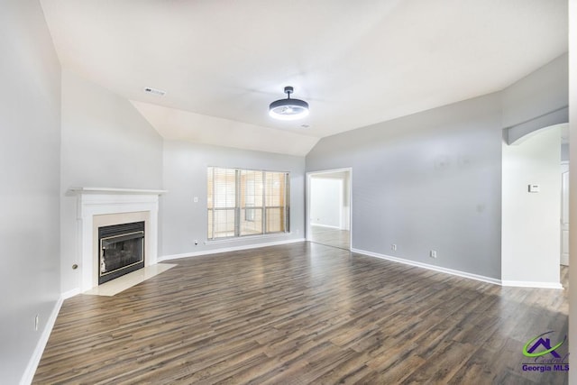 319 Smithville Church Rd, Warner Robins, GA 31088 - unfurnished living room featuring wood finished floors, vaulted ceiling, baseboards, a fireplace with flush hearth, and arched walkways