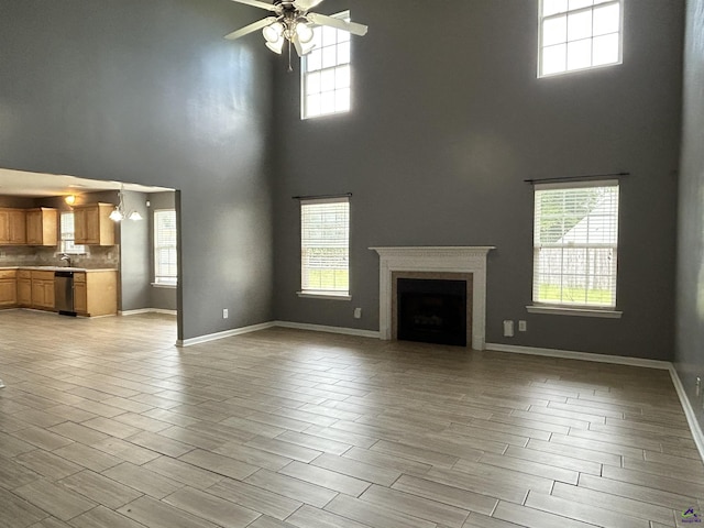 103 Lattice Bnd, Bonaire, GA 31005 - unfurnished living room with a towering ceiling, ceiling fan, baseboards, light wood-style flooring, and a sink