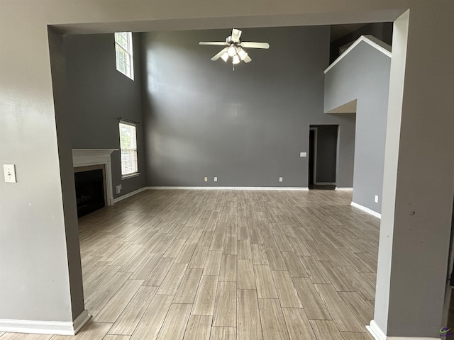 103 Lattice Bnd, Bonaire, GA 31005 - unfurnished living room with a towering ceiling, a ceiling fan, light wood-style floors, a fireplace, and baseboards