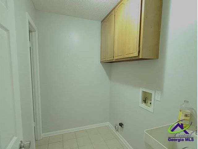 115 Friar Tuck Ave, Warner Robins, GA 31088 - laundry area with cabinet space, hookup for a washing machine, a textured ceiling, baseboards, and light tile patterned floors