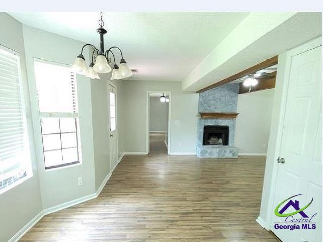 115 Friar Tuck Ave, Warner Robins, GA 31088 - unfurnished living room with baseboards, a chandelier, wood finished floors, and healthy amount of natural light