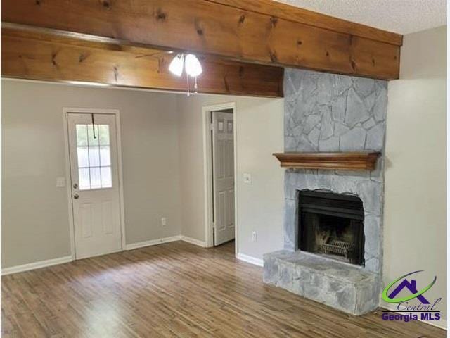 115 Friar Tuck Ave, Warner Robins, GA 31088 - unfurnished living room featuring a stone fireplace, wood finished floors, and baseboards