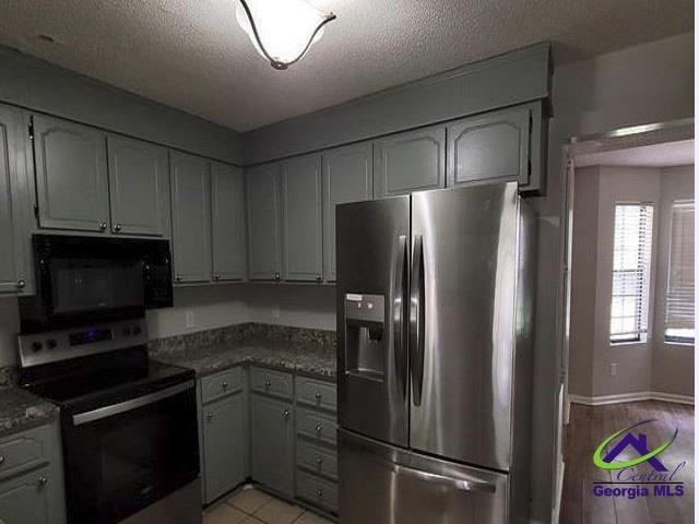 115 Friar Tuck Ave, Warner Robins, GA 31088 - kitchen featuring stainless steel fridge with ice dispenser, electric range oven, black microwave, a textured ceiling, and baseboards