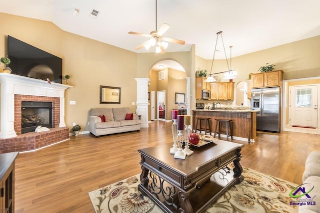 201 Loudon Hill Dr, Warner Robins, GA 31088 - living area featuring arched walkways, light wood-style flooring, a ceiling fan, a brick fireplace, and high vaulted ceiling