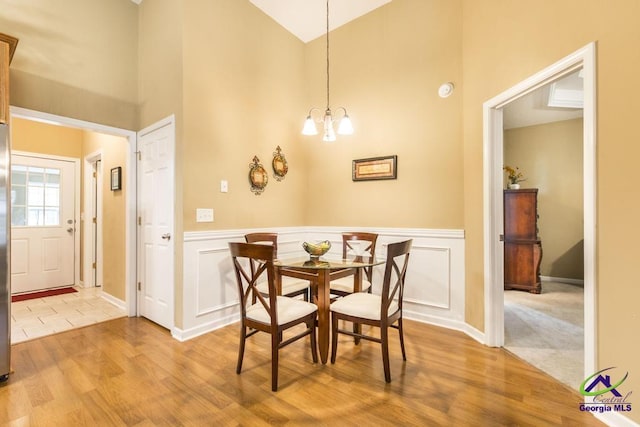 201 Loudon Hill Dr, Warner Robins, GA 31088 - dining area with high vaulted ceiling, light wood-type flooring, a chandelier, a wainscoted wall, and baseboards