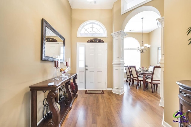 201 Loudon Hill Dr, Warner Robins, GA 31088 - entrance foyer featuring ornate columns, wood finished floors, a chandelier, a towering ceiling, and arched walkways