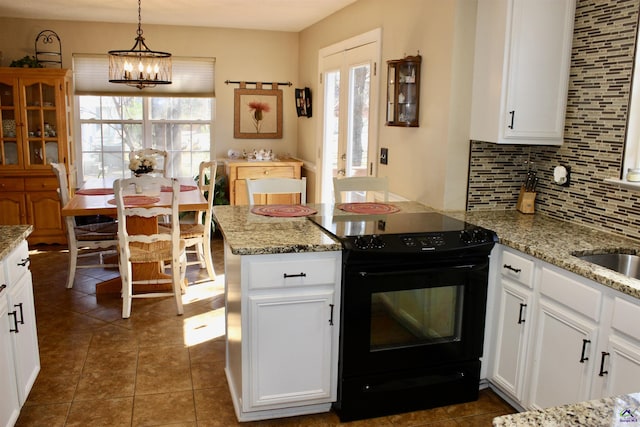 303 Shane, Perry, GA 31069 - kitchen with electric range, a peninsula, tasteful backsplash, white cabinets, and a chandelier