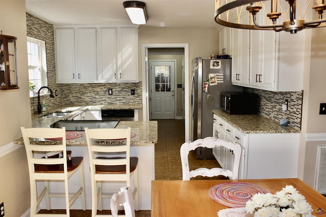 303 Shane, Perry, GA 31069 - kitchen with a chandelier, a sink, stainless steel microwave, backsplash, and white cabinetry