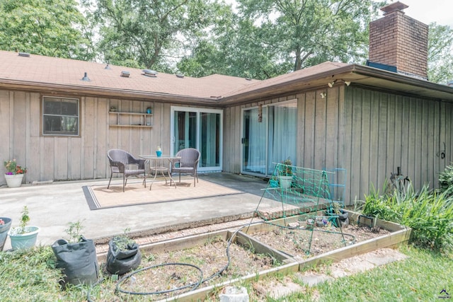 826 Edward Pl, Macon, GA 31204 - back of house featuring a vegetable garden, a chimney, a patio area, and board and batten siding