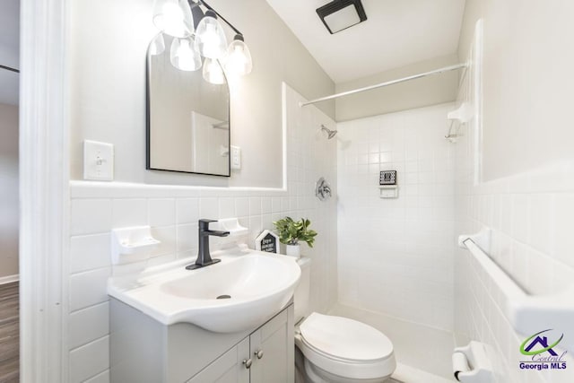123 Robinhood Dr, Warner Robins, GA 31088 - full bathroom featuring vanity, a tile shower, toilet, tile walls, and a wainscoted wall