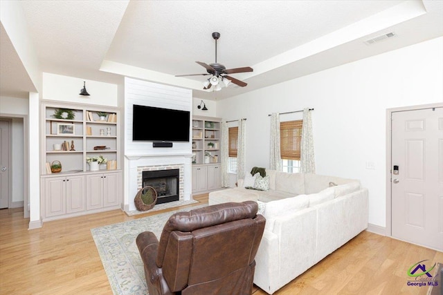 133 Gage Dr, Perry, GA 31069 - living area with a tray ceiling, ceiling fan, light wood-style flooring, a fireplace, and baseboards