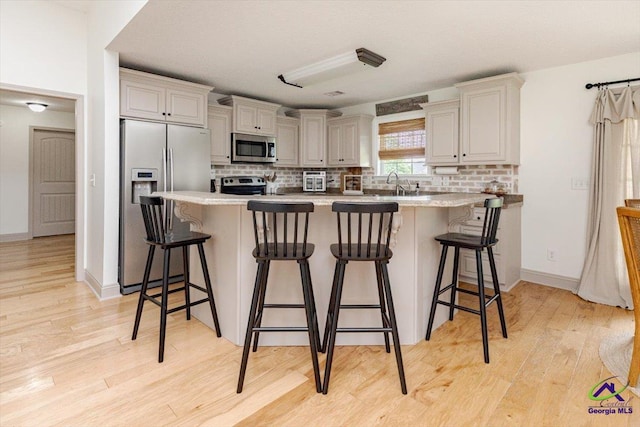 133 Gage Dr, Perry, GA 31069 - kitchen featuring stainless steel appliances, decorative backsplash, and light wood-style flooring