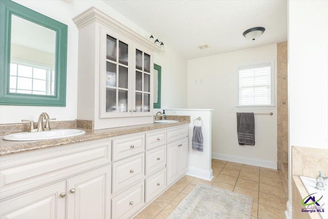 133 Gage Dr, Perry, GA 31069 - full bath featuring double vanity, tiled tub, tile patterned floors, and baseboards