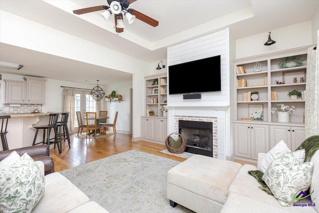 133 Gage Dr, Perry, GA 31069 - living area with a ceiling fan, light wood-style floors, a fireplace with flush hearth, a tray ceiling, and baseboards