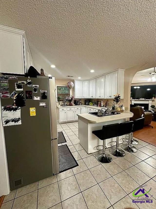 108 Christine, Perry, GA 31069 - kitchen featuring freestanding refrigerator, a peninsula, a textured ceiling, white cabinetry, and arched walkways