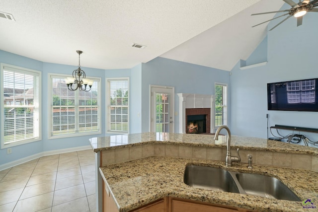 107 Rachael Ln, Warner Robins, GA 31088 - kitchen featuring open floor plan, light stone countertops, hanging light fixtures, light tile patterned flooring, and a fireplace