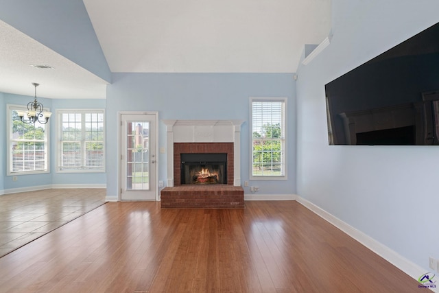 107 Rachael Ln, Warner Robins, GA 31088 - unfurnished living room with a chandelier, a fireplace, healthy amount of natural light, wood finished floors, and high vaulted ceiling