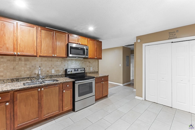 2105 Mutual Ave, Macon, GA 31204 - kitchen featuring appliances with stainless steel finishes, a sink, brown cabinets, tasteful backsplash, and recessed lighting