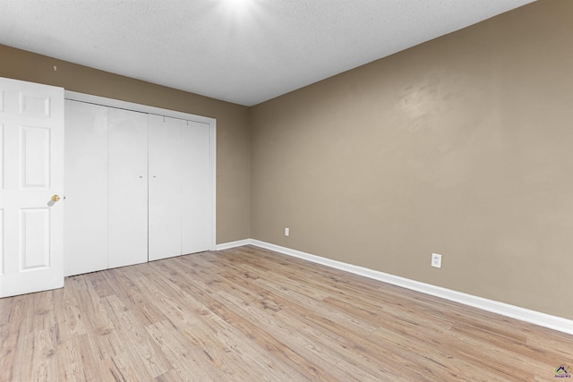 2105 Mutual Ave, Macon, GA 31204 - unfurnished bedroom featuring light wood-style flooring, baseboards, a closet, and a textured ceiling