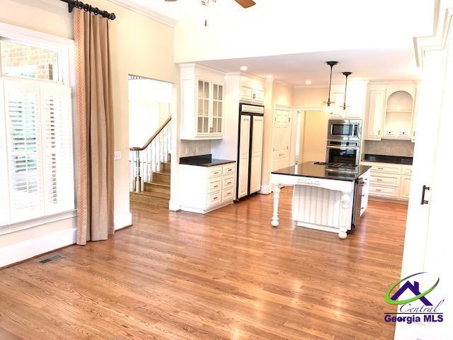 113 Troon Way, Macon, GA 31210 - kitchen with built in appliances, dark countertops, ornamental molding, a ceiling fan, and light wood-style flooring