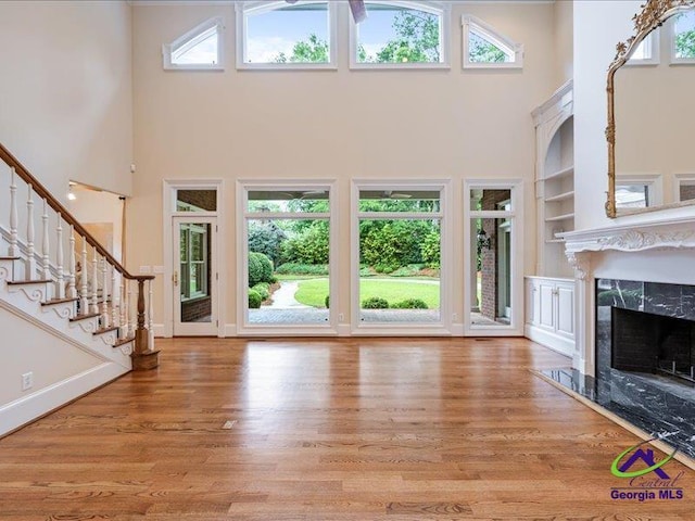 113 Troon Way, Macon, GA 31210 - unfurnished living room featuring a towering ceiling, built in shelves, plenty of natural light, wood finished floors, and stairway