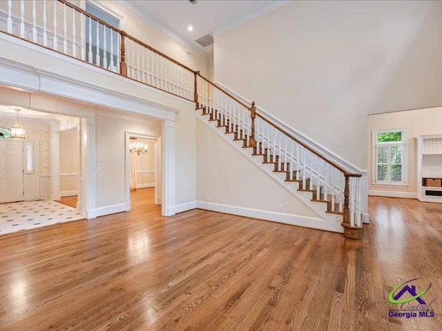 113 Troon Way, Macon, GA 31210 - unfurnished living room featuring a high ceiling, ornamental molding, wood finished floors, a chandelier, and stairs