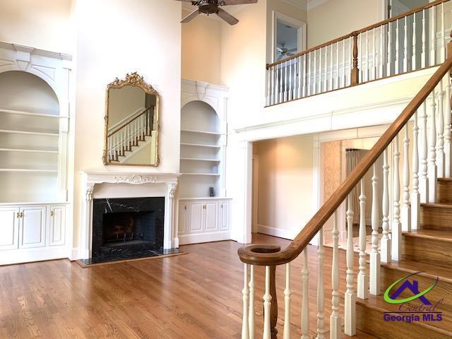 113 Troon Way, Macon, GA 31210 - stairway featuring built in features, ceiling fan, a fireplace, wood finished floors, and a towering ceiling