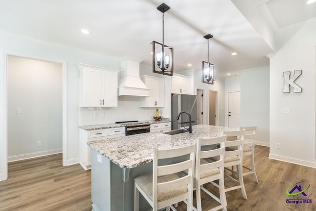 107 Field View Ln, Kathleen, GA 31047 - kitchen with wall chimney range hood, a sink, appliances with stainless steel finishes, an island with sink, and white cabinetry