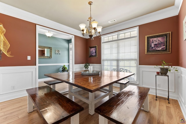 2725 Moseley Rd, Byron, GA 31008 - dining area featuring a wainscoted wall, a chandelier, a decorative wall, crown molding, and light wood-type flooring
