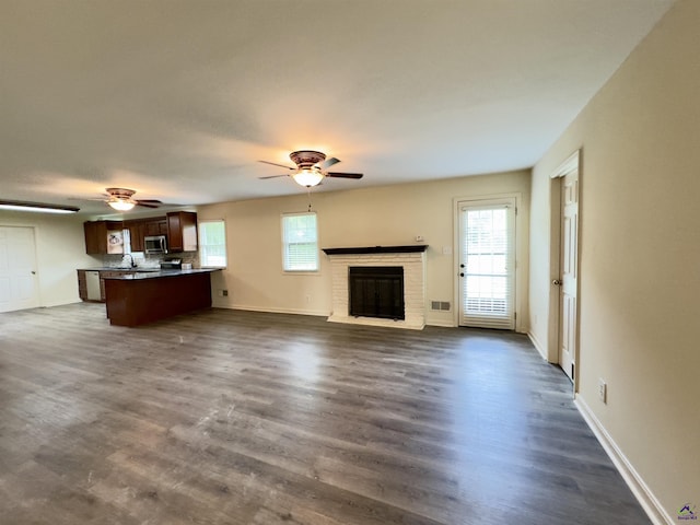 221 Fox Hound Dr, Byron, GA 31008 - unfurnished living room with a ceiling fan, a brick fireplace, dark wood-style flooring, and baseboards