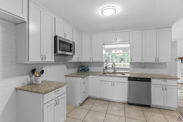 110 Ensenada Way, Warner Robins, GA 31088 - kitchen featuring stainless steel appliances, a sink, light stone counters, a textured ceiling, and white cabinetry