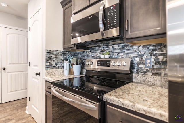 224 Allentown Ln, Macon, GA 31216 - kitchen with stainless steel appliances, dark brown cabinets, light wood-style flooring, decorative backsplash, and light stone counters