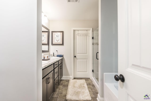 224 Allentown Ln, Macon, GA 31216 - full bathroom with stone tile flooring, double vanity, a stall shower, a bathtub, and baseboards