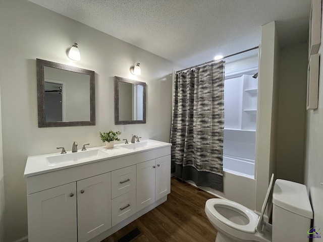 571 Duncan Ave, Unadilla, GA 31091 - full bathroom featuring toilet, double vanity, wood finished floors, a textured ceiling, and shower / bath combo with shower curtain