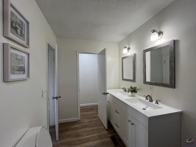 571 Duncan Ave, Unadilla, GA 31091 - bathroom with wood finished floors, a textured ceiling, double vanity, and baseboards
