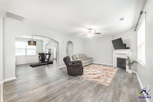 318 Flowing Meadows Dr, Bonaire, GA 31047 - living area featuring arched walkways, a ceiling fan, wood finished floors, a fireplace, and baseboards