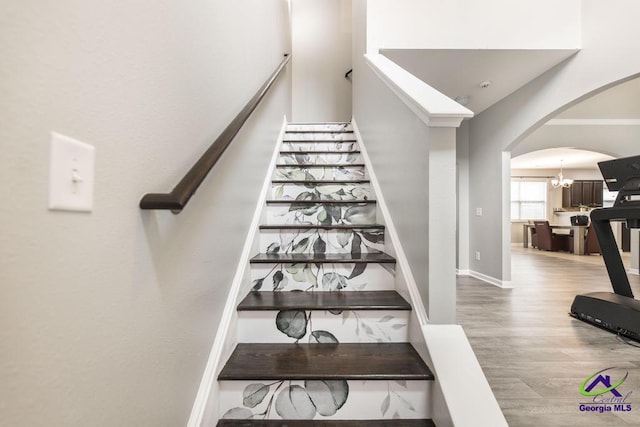 318 Flowing Meadows Dr, Bonaire, GA 31047 - stairway featuring arched walkways, wood finished floors, a chandelier, and baseboards