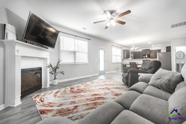 318 Flowing Meadows Dr, Bonaire, GA 31047 - living room featuring a ceiling fan, a glass covered fireplace, wood finished floors, baseboards, and a chandelier