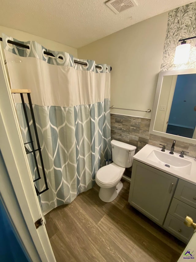 403 Fieldstone Rd, Warner Robins, GA 31093 - bathroom with wood finished floors, a wainscoted wall, a textured ceiling, vanity, and toilet