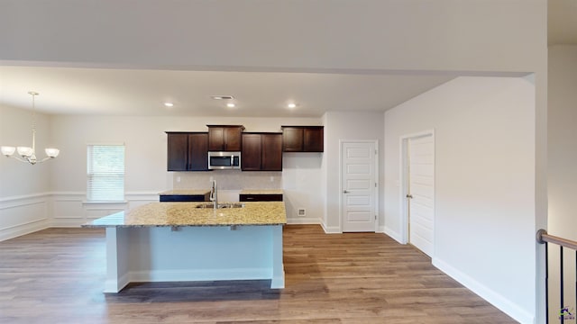444 Southern Oaks Dr, Macon, GA 31216 - kitchen featuring stainless steel microwave, a sink, dark brown cabinets, wood finished floors, and a center island with sink
